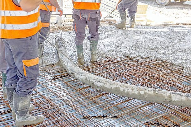 A group of construction workers standing on top of concrete.