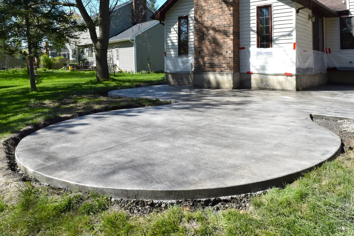 A concrete patio in the middle of a yard.