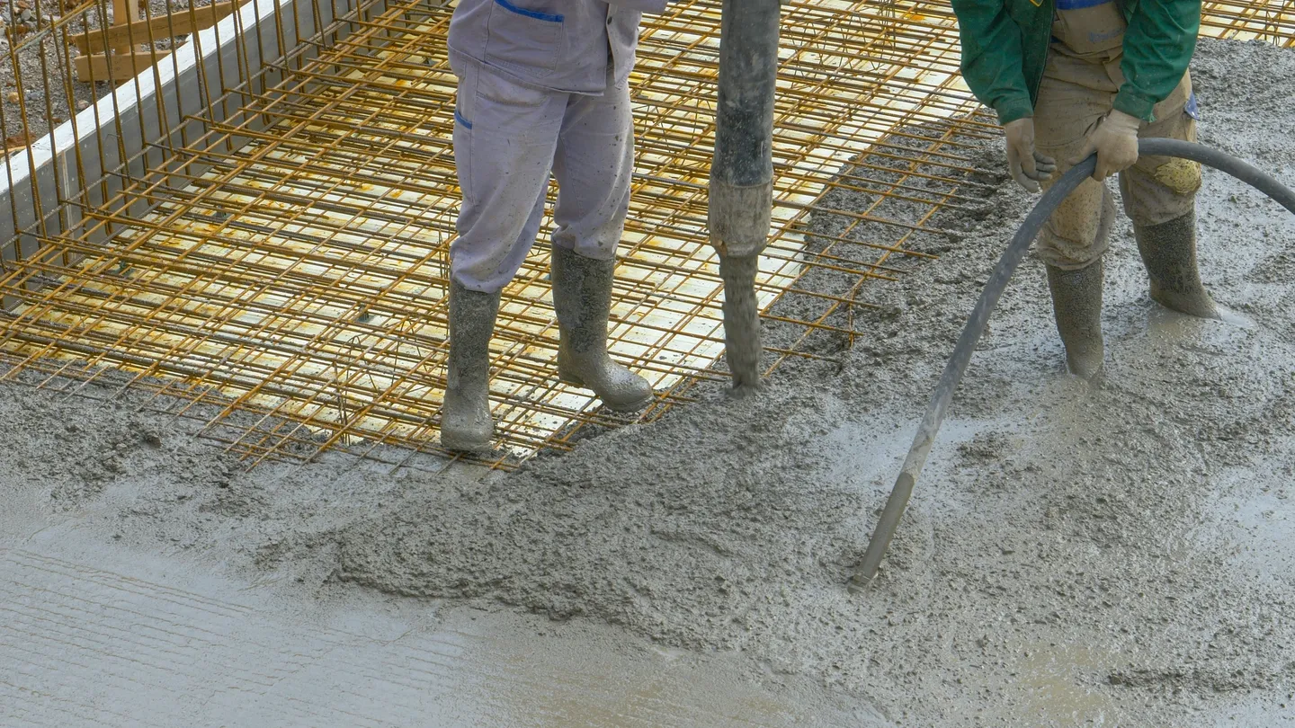 A man standing on top of concrete with cement mixer.